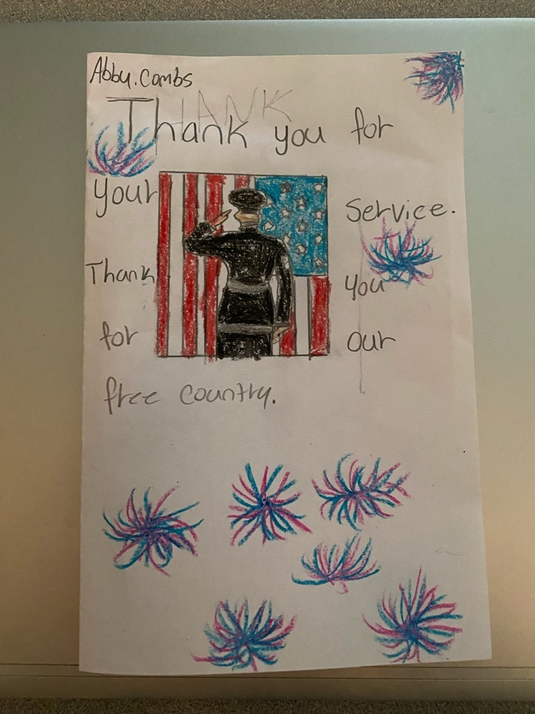 a Veterans Day card with a student drawing of a soldier saluting in front of a flag