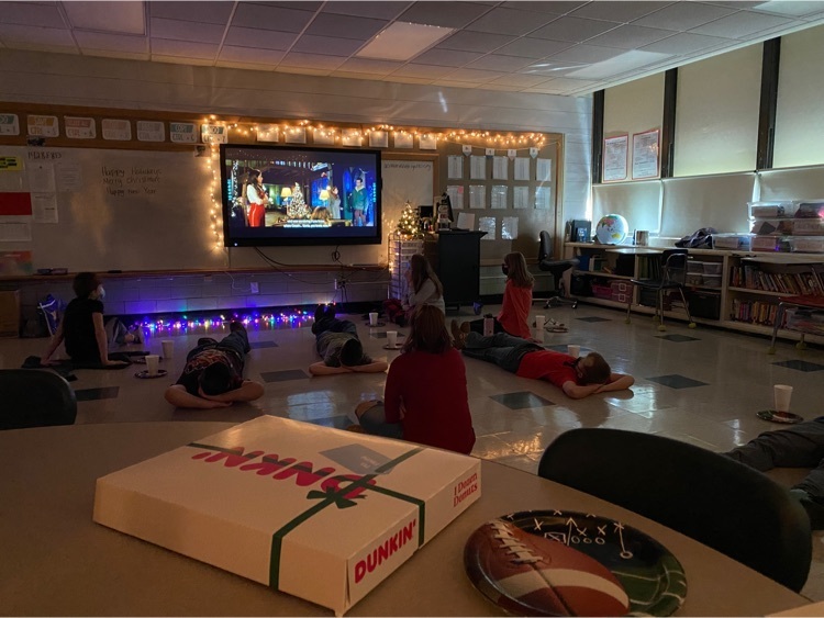students sitting on the floor watching a movie and enjoying treats